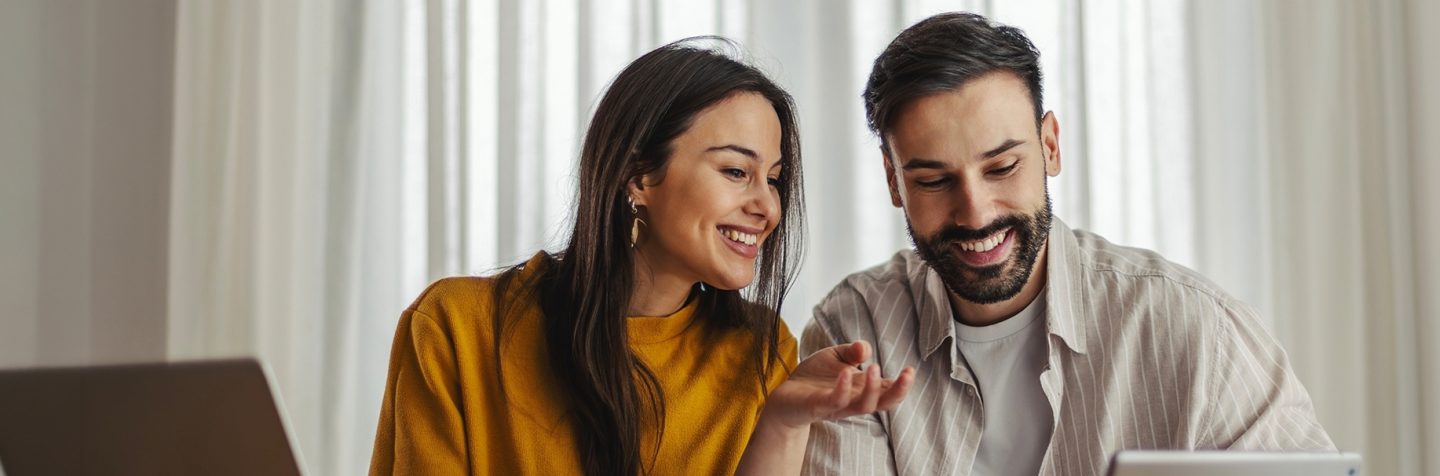 Smiling couple looking at a tablet together.