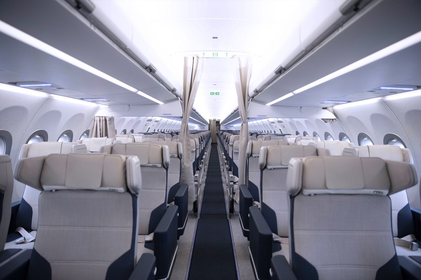 Het gangpad van het vliegtuig met de gordijnen open en zicht op Premium Economy-klasse en de rest van de cabine. 