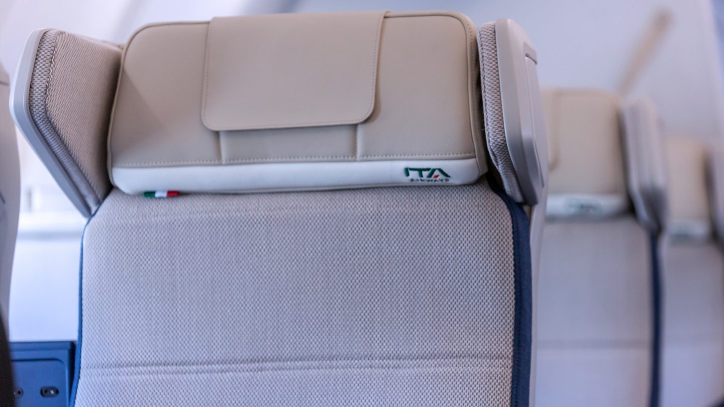 Close-up van de Premium Economy-hoofdsteun met ITA Airways-borduursel en de Italiaanse vlag.